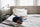 Zinus Soft upholstered bed with white bedding in a calm, airy bedroom; a toddler rests comfortably on the mattress, conveying gentle support, everyday comfort, and a peaceful sleep environment designed for family-friendly use.