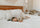 Small child sleeping on a white bed with textured pillows and soft neutral decor, creating a calm, cozy bedroom setting with natural woven accents