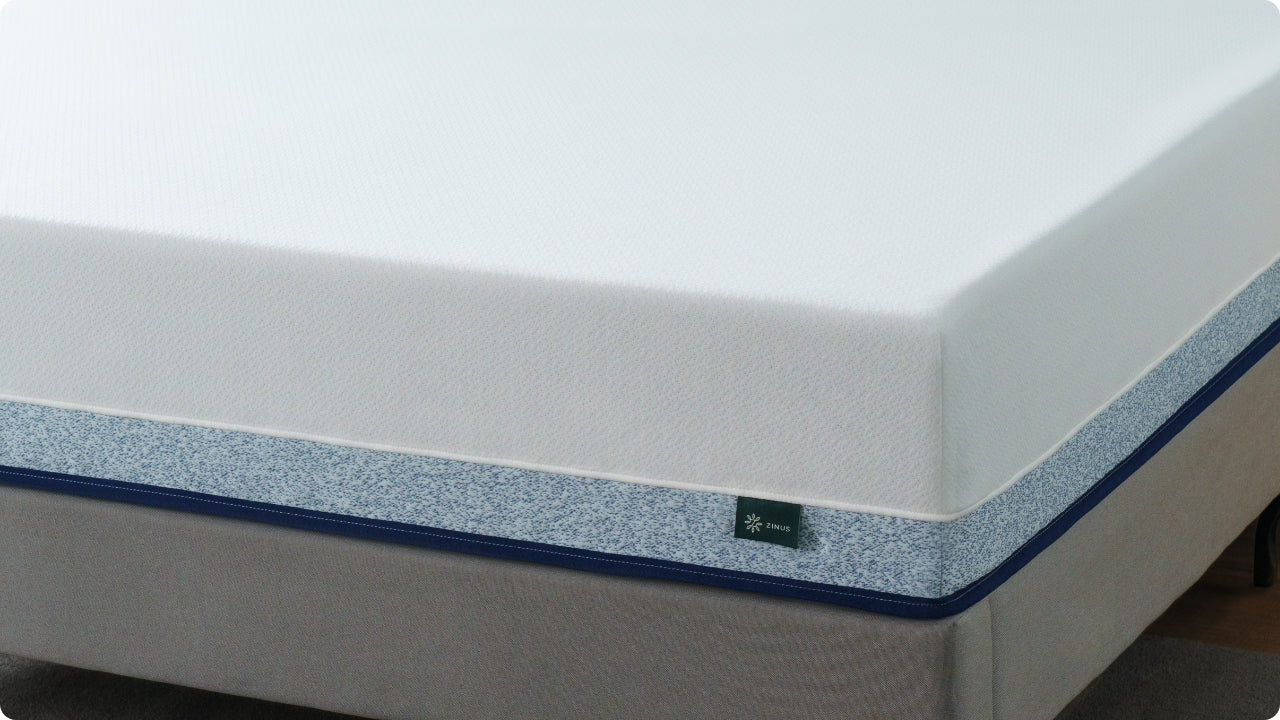 Memory foam mattress with a smooth white top panel and a blue-speckled side design resting on a gray foundation, showing clean edges and supportive construction.