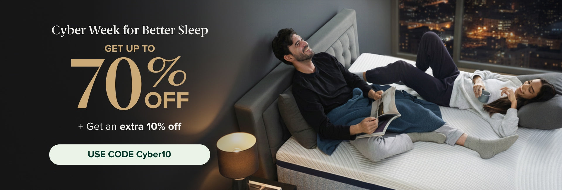 Cyber Week for Better Sleep. Get up to 70% off. + Get an extra 10% off. Use code Cyber10.” Below the text, two adults relax on a tufted-headboard bed; one reads a magazine while the other holds a mug, lying on a white contoured mattress in a high-rise bedroom at night.