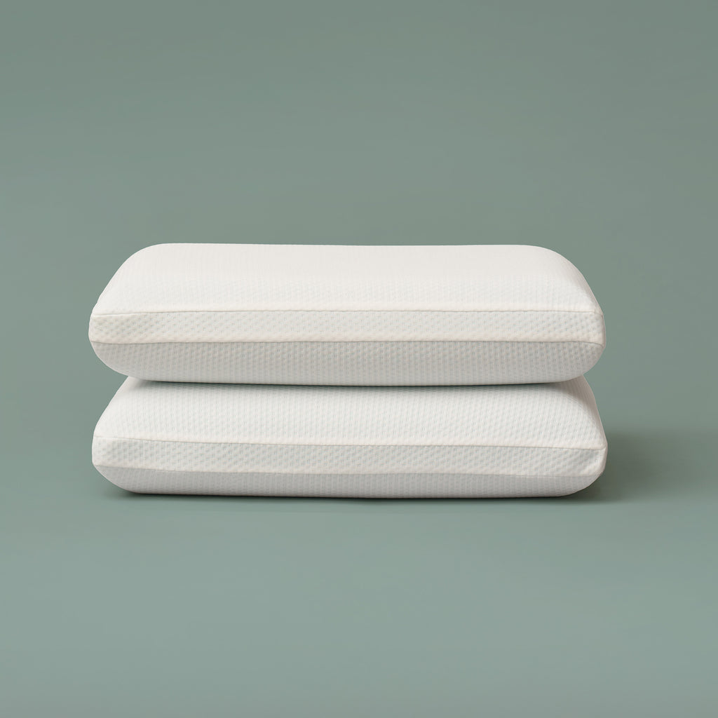 Set of two rectangular cooling memory foam pillows stacked against a muted green background, featuring smooth white breathable knit covers and supportive shape designed for comfort and temperature regulation during sleep 