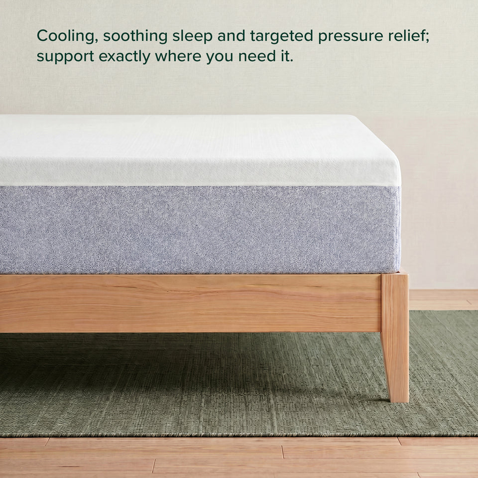 Zinus Balanced Comfort Signature Memory Foam Mattress, side view close-up of the white knit cover and blue-gray woven base fabric on a natural wood platform frame, with on-image text reading: 'Cooling, soothing sleep and targeted pressure relief; support exactly where you need it.