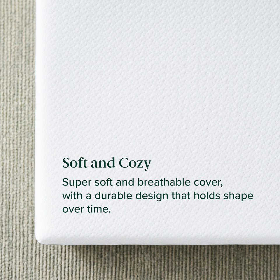 Zinus Balanced Comfort Core Memory Foam Mattress, close-up of the soft knit top cover texture resting on a woven area rug, labeled 'Soft and Cozy' with supporting text: 'Super soft and breathable cover, with a durable design that holds shape over time.
