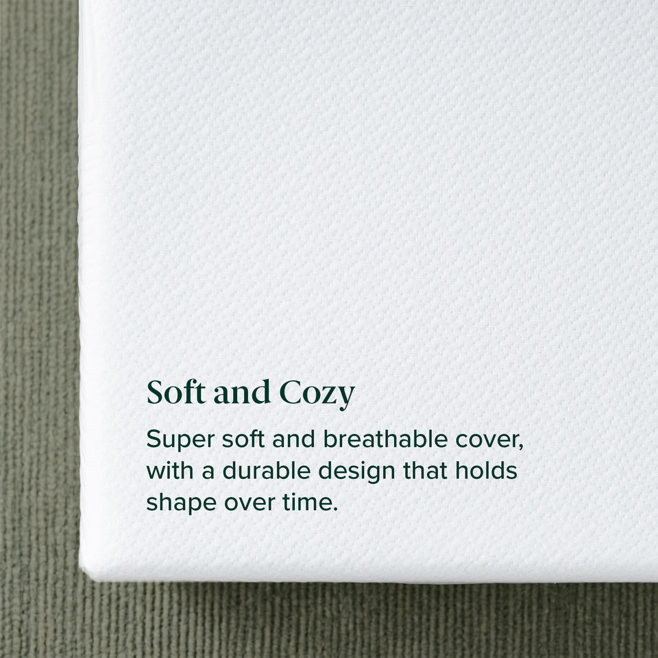 Zinus Balanced Comfort Signature Memory Foam Mattress, close-up of the soft knit top cover texture resting on a woven area rug, labeled 'Soft and Cozy' with supporting text: 'Super soft and breathable cover, with a durable design that holds shape over time.