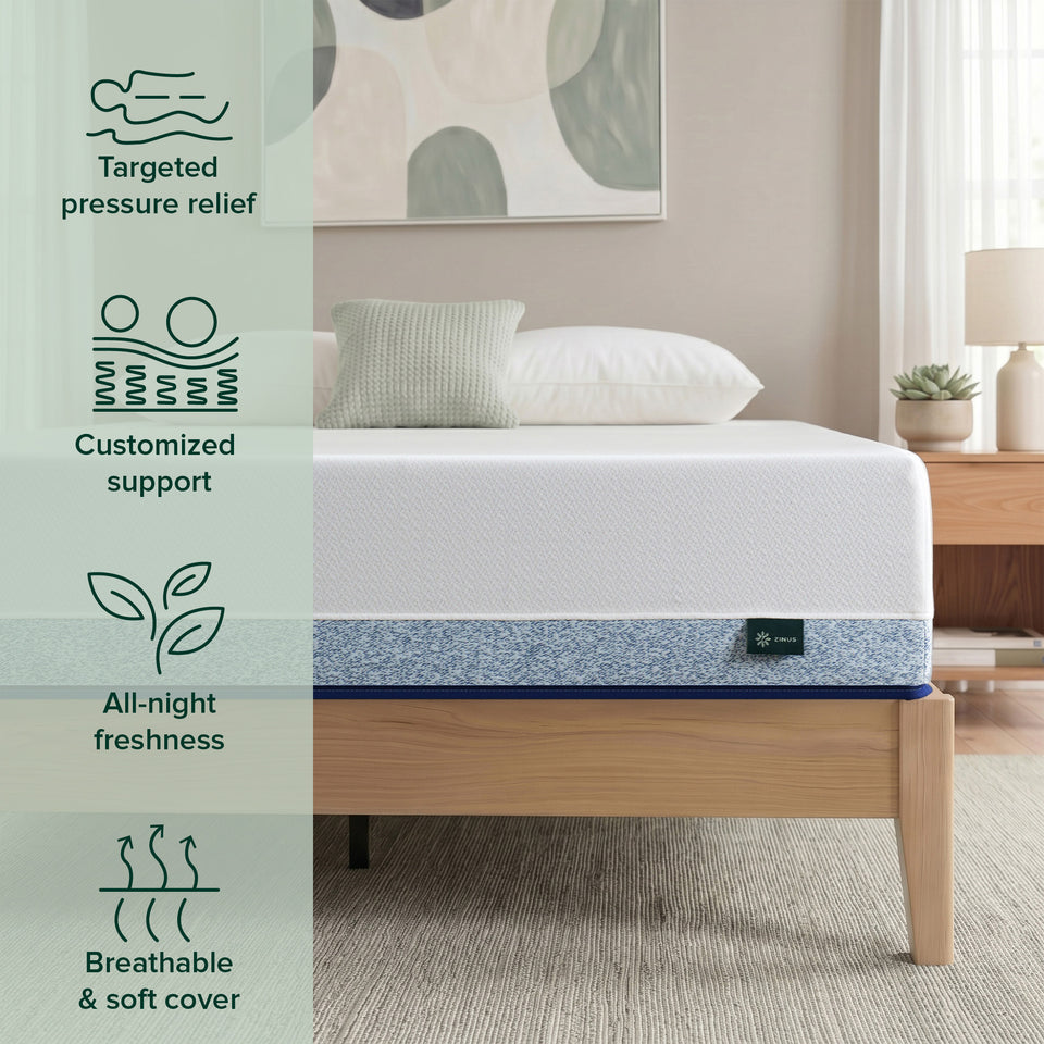 Lifestyle bedroom photo of Zinus Original Green Tea Hybrid Mattress, Queen size, on a light wood platform bed frame with white and sage pillows, framed abstract art, nightstand, lamp, and succulent plant. Overlaid on the left are four icons with text: reclining figure icon labeled 'Targeted pressure relief'; coil and wave icon labeled 'Customized support'; leaf icon labeled 'All-night freshness'; airflow arrows icon labeled 'Breathable & soft cover'. A Zinus logo tag is visible on the mattress corner.
