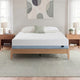 Zinus Original Green Tea Memory Foam Mattress, Queen, on light wood platform bed frame in bright bedroom with white and sage pillows, matching nightstands, lamps, books, and a succulent plant.