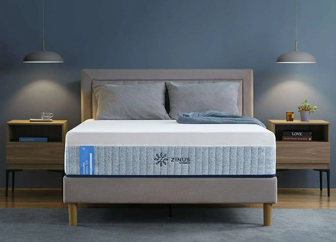 Zinus Cooling Green Tea Hybrid mattress on upholstered bed with gray headboard, styled in bedroom with twin wooden nightstands, gray bedding, and pendant lights