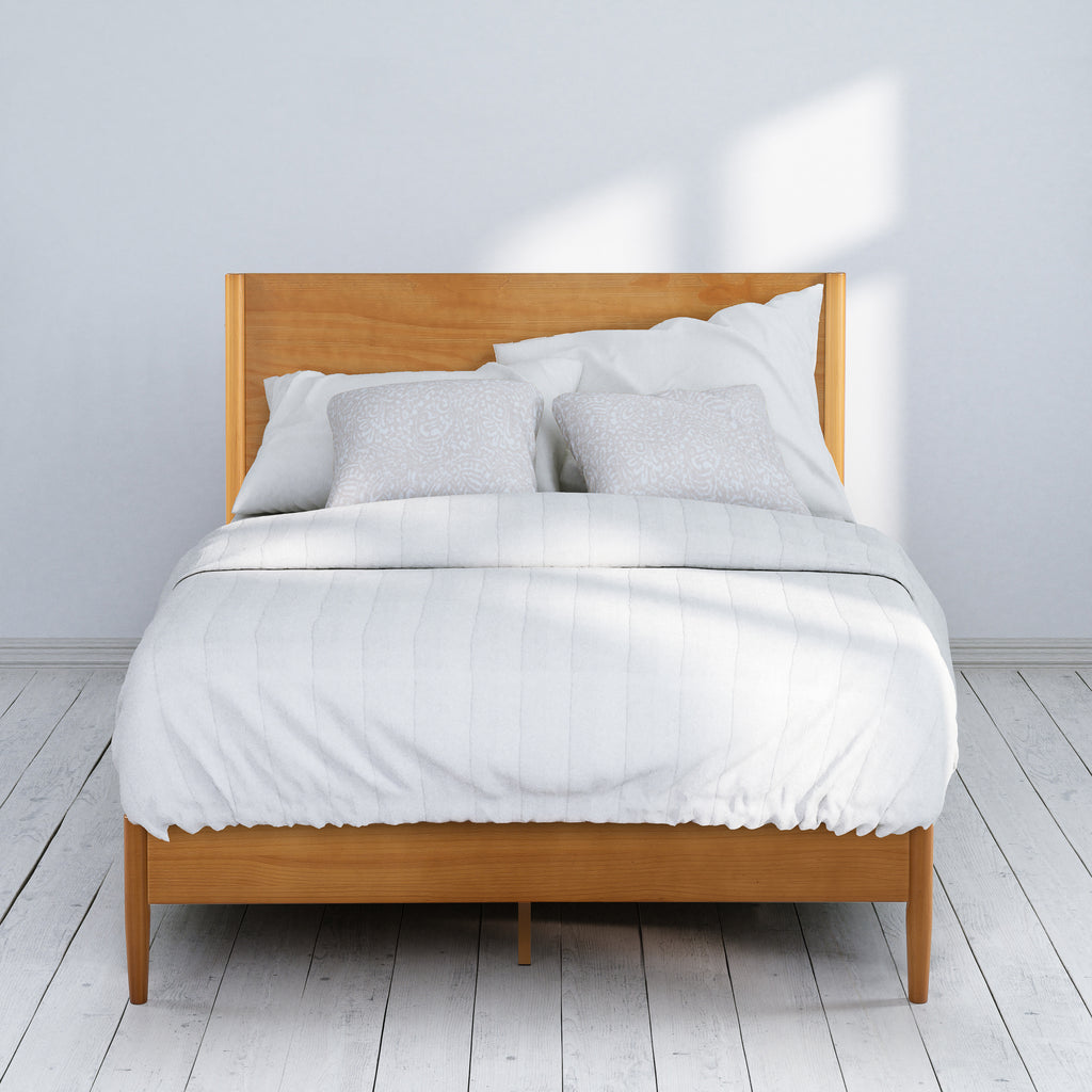 Zinus Allen Wood Platform Bed Frame shown fully dressed with white bedding in a bright bedroom. Natural wood frame and sleek headboard highlight clean Scandinavian-inspired style. Slatted foundation offers reliable mattress support while 12-inch clearance provides storage space.